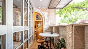Un espace intérieur accueillant avec une table et des chaises en bois, un mur en briques et une grande fenêtre donnant sur un paysage verdoyant.