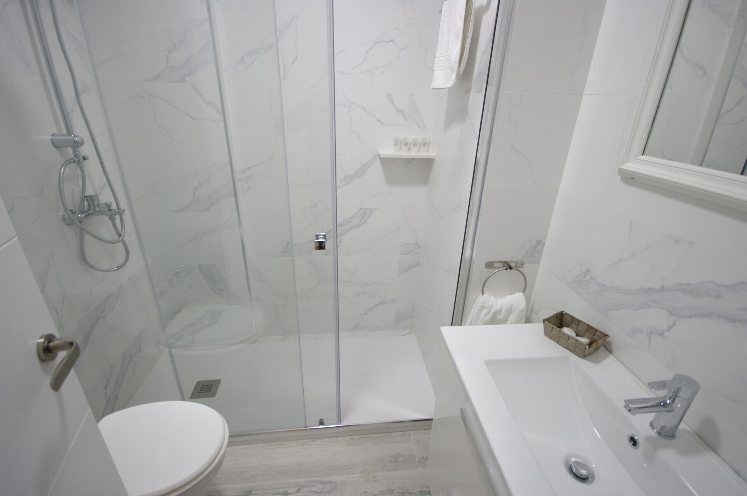 Ein modernes Badezimmer mit einer Duschkabine aus Glas, einer weißen Toilette und einem Waschbecken mit Spiegel darüber.