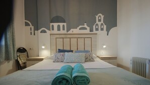 Un letto rifatto con cura, asciugamani arrotolati, una testiera, lampade da comodino e un murale con sagome architettoniche.