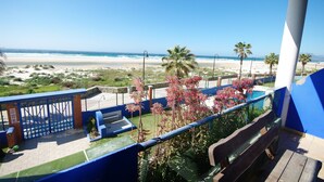 Un balcone con vista sulla spiaggia, palme e una piscina.