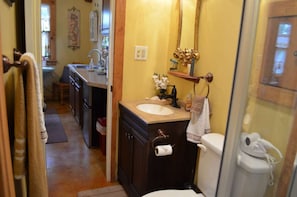 Une petite salle de bain avec un lavabo, des toilettes et un miroir. Une serviette est accrochée au mur.