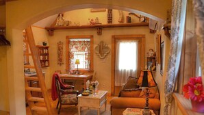 A cozy living room with a wooden staircase, a dining table, a sofa, and a small table with a lamp. - Rumpelstilzchen Cottage (#2) (Fredericksburg)