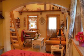 Una sala de estar acogedora con una escalera de madera, una mesa de comedor, un sofá y una mesita con una lámpara.
