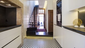 Una cocina moderna con encimera negra, armarios blancos y suelo estampado.