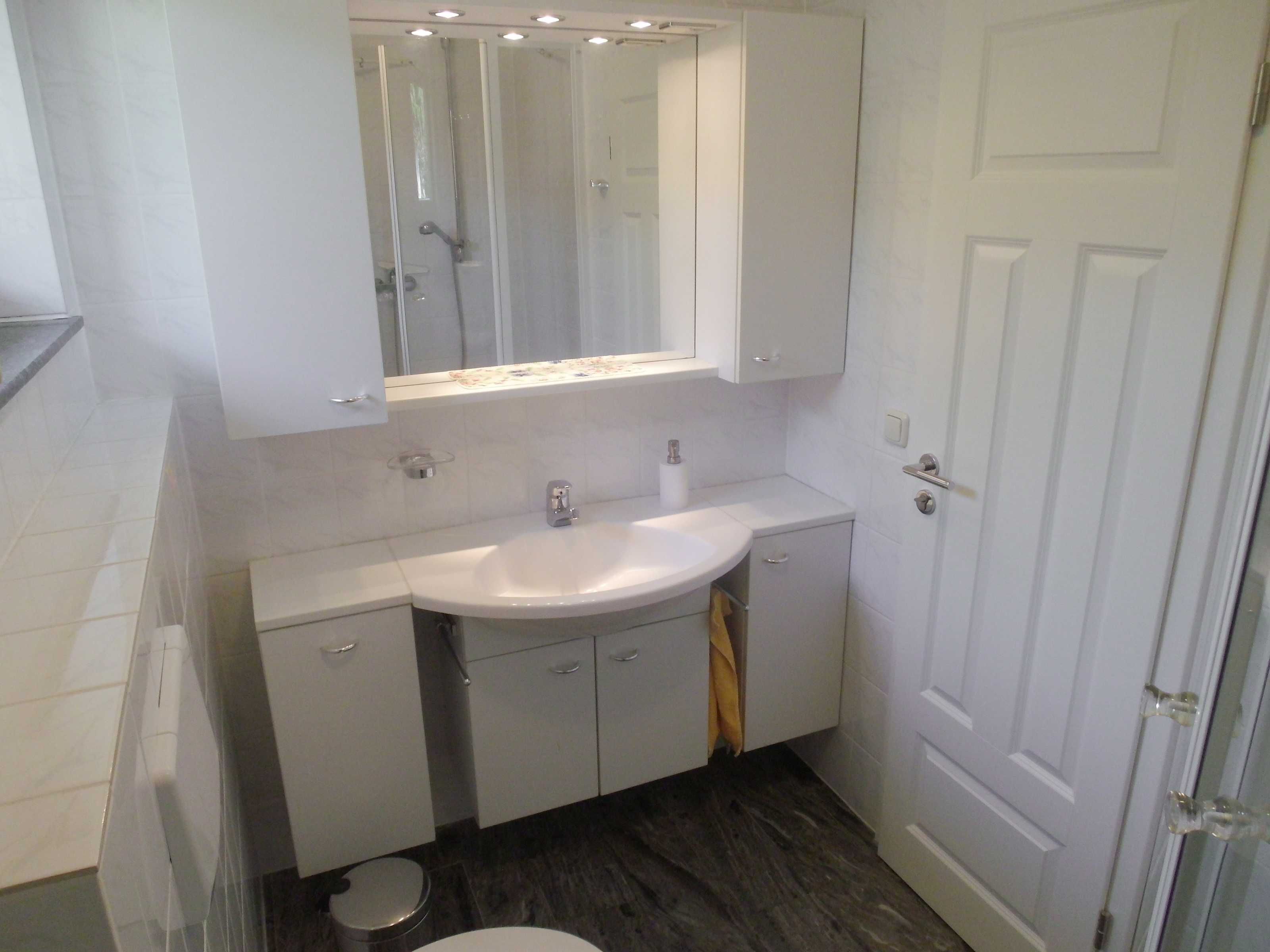A bathroom with a white sink, mirror, and toilet.