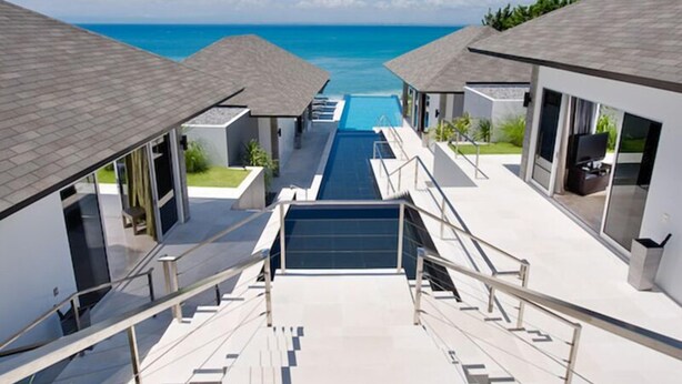 Et moderne resort med en central pool, flere gæsteværelser og udsigt over havet.