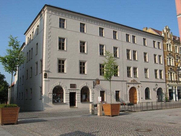 A historic building with a symmetrical facade, multiple windows, and a central entrance with an archway.