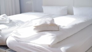 A neatly made bed with white linens and a folded towel on the bed. - Double room - Cranach hostel Wittenberg (Lutherstadt Wittenberg)