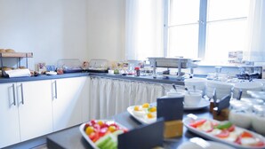 A modern kitchen with white cabinets, a countertop with various food items, and a window providing natural light. - Double room - Cranach hostel Wittenberg (Lutherstadt Wittenberg)