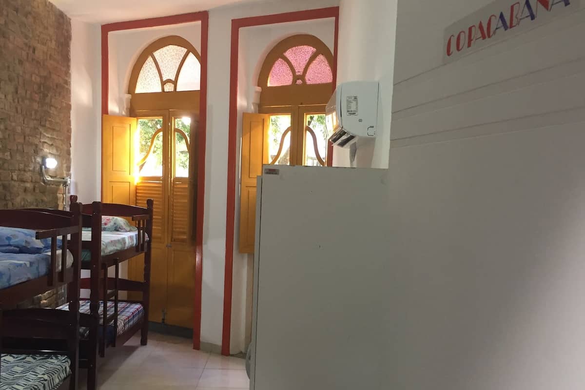 Una habitación con literas, un refrigerador y una puerta que da a otra habitación.