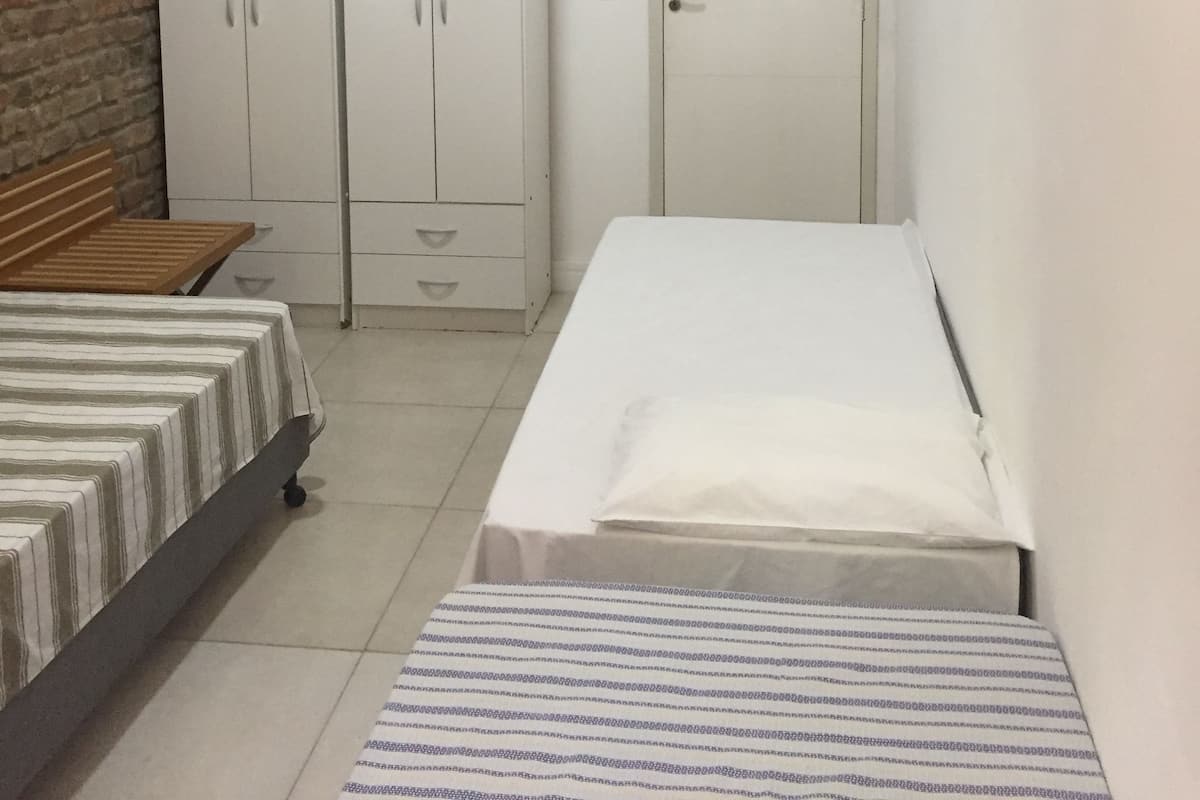 Una habitación pequeña y limpia, con cama, armario y puerta.