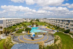 Ein Resort mit einem zentral gelegenen Schwimmbad, mehreren Balkonen und gepflegten Rasenflächen.