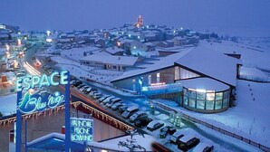 A snow-covered town with a neon sign for 'ESPACE Blue Ridge' and a building with a glass facade.