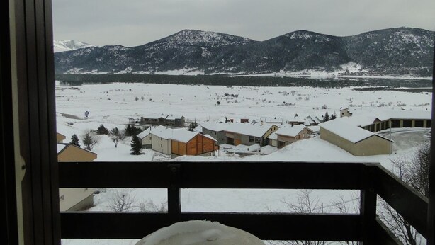 A snowy landscape with houses and mountains in the background.
