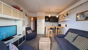 A modern living room with a TV, sofa, and a small dining table.