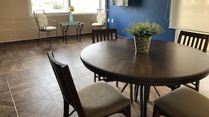 Une salle de conférence équipée d’une table ronde, de chaises, d’une plante en pot, d’un téléviseur fixé au mur et d’une fenêtre donnant sur l’extérieur.