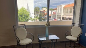 Une pièce avec deux chaises, une petite table et un vase rempli de fleurs.