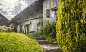 Un bâtiment en bois avec un toit en pente, un banc à l’extérieur et une pelouse bien entretenue.