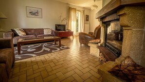 Una sala de estar con chimenea, un sofá, una mesa de centro y un televisor.