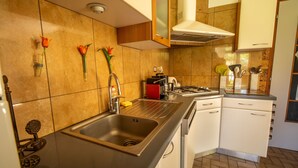 Una cocina con pileta de acero inoxidable, armarios blancos y un salpicadero azulejado.