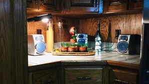 A kitchen with wooden cabinets, a countertop with various items including a radio, a bottle, and a small speaker.