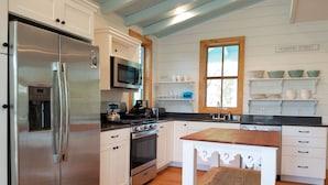 Una cucina moderna con mobili bianchi, elettrodomestici in acciaio inossidabile e un tavolo di legno.