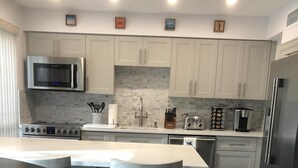 A modern kitchen with white cabinets, stainless steel appliances, and a dark wooden island.