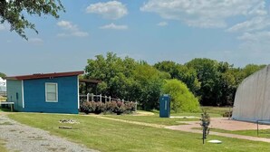 Un petit bâtiment bleu avec un toit rouge, un chemin de gravier et une pelouse verte.