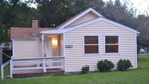 Une petite maison de plain-pied avec un porche à l’avant, une cheminée et une boîte aux lettres.