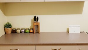 Una cocina con armarios color beige, una encimera y varios utensilios, incluyendo frascos y una planta.