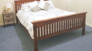 Un dormitorio con una cama de madera, una mesita de noche y una pared lisa.