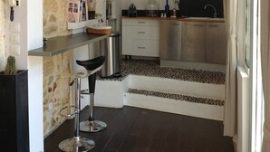 A modern kitchen with a stone accent wall, a hanging pendant light, and a clock on the wall. - Montpellier center cozy house (Montpellier)