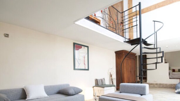 A modern living room with a grey sofa, a wooden coffee table, and a potted plant. A spiral staircase leads to an upper level. - Montpellier center cozy house (Montpellier)