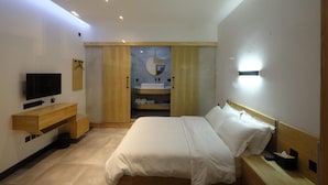 Ein modernes Schlafzimmer mit Bett, Nachttisch, Fernseher, Holzschrank und integriertem Waschbecken.