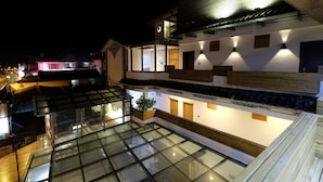 Ein modernes Gebäude mit einer terrasse mit Glasdach, Holzakzenten und Innenbeleuchtung.