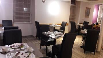 A dining area with tables and chairs, a window with blinds, and a ceiling with hanging spherical decorations.