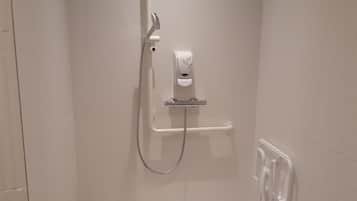 A small, modern shower area with a handheld showerhead, a soap dispenser, and a towel rack.