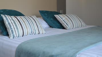 A bed with striped pillows and a teal blanket.