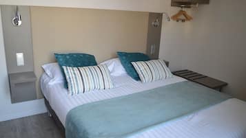 Cama bem arrumada com almofadas listradas e um cobertor azul claro.