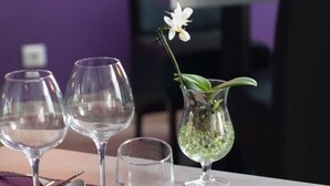 Een eettafel gedekt met wijnkaraffen, een bord, bestek en een vaas met een bloem.