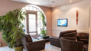 Een moderne lobby met een grote potplant, leren banken, een flatscreen televisie en een gebogen muur.