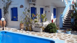 A white building with blue accents, a swimming pool, and a staircase leading to a balcony. - Holiday apartment with sea view and mountains view (Marathokampos)