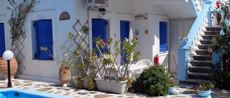 Un bâtiment blanc agrémenté de touches de bleu, une piscine et un escalier menant à un balcon.