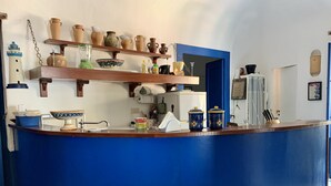 Una cocina con encimera azul, estantes con cerámica, un refrigerador blanco y una puerta azul.