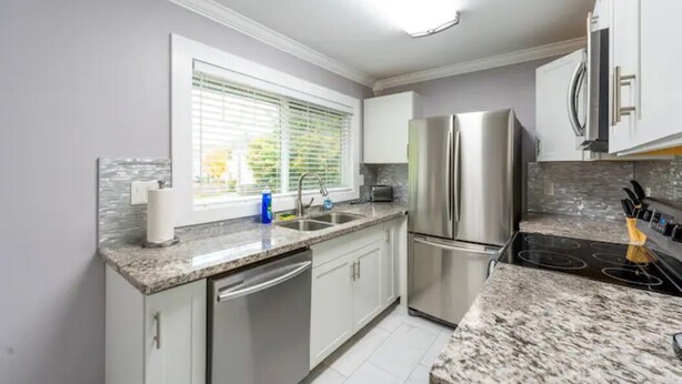 A modern kitchen with a stainless steel refrigerator, double sink, and granite countertops. - DOWNTOWN TACOMA HOUSE OF GRAY #4 (Tacoma)