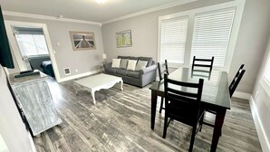 A living room with a grey sofa, a white coffee table, and a dining table with chairs. - DOWNTOWN TACOMA HOUSE OF GRAY #4 (Tacoma)