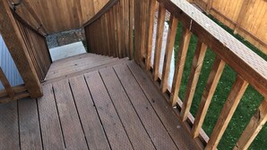 A wooden deck with a metal railing and a small step leading to a grassy area. - DOWNTOWN TACOMA HOUSE OF GRAY #4 (Tacoma)