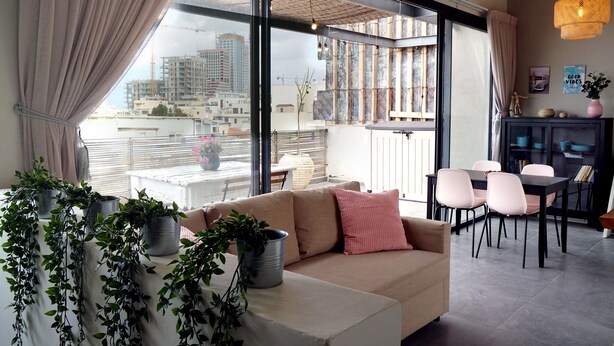 Un salon moderne comprenant un canapé, une table à manger, des chaises et de grandes fenêtres donnant sur la ville.