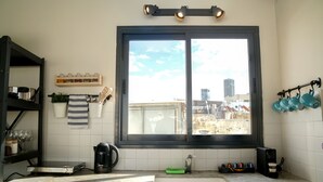 Une cuisine avec une fenêtre, une machine à café et un bloc à couteaux.