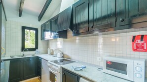 Una cocina con gabinetes oscuros, un microondas, un lavavajillas y una ventana.